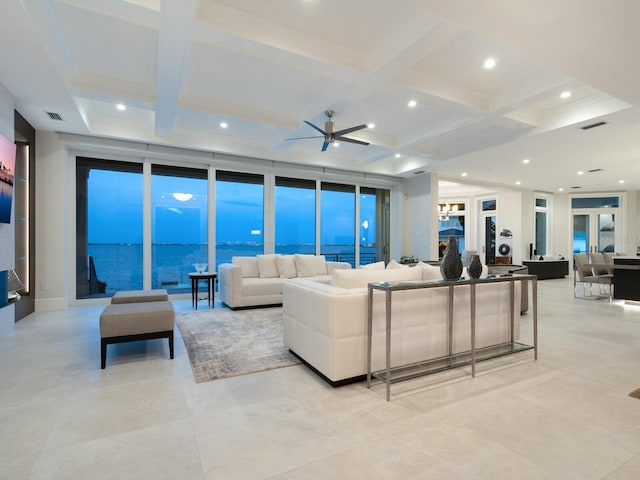 living room featuring ceiling fan, coffered ceiling, a wall of windows, beamed ceiling, and a water view