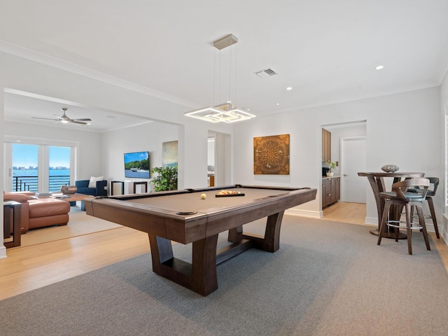 game room with a water view, billiards, light hardwood / wood-style flooring, ceiling fan, and ornamental molding