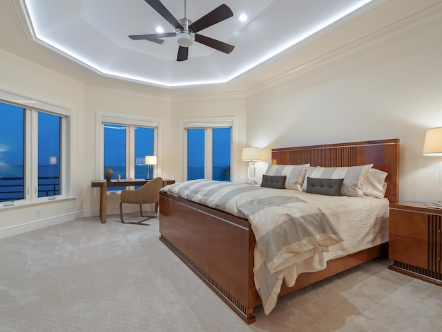 bedroom with light carpet, a tray ceiling, ceiling fan, and crown molding