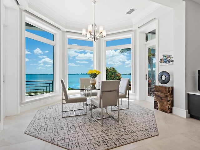 dining room with crown molding, a water view, and a notable chandelier