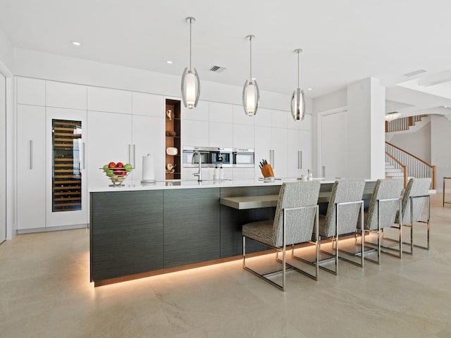 kitchen featuring wall oven, wine cooler, white cabinets, and pendant lighting