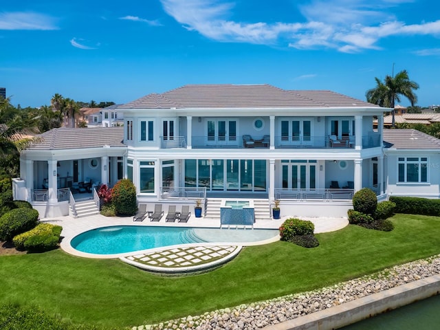 rear view of house with a yard, a patio, and a balcony