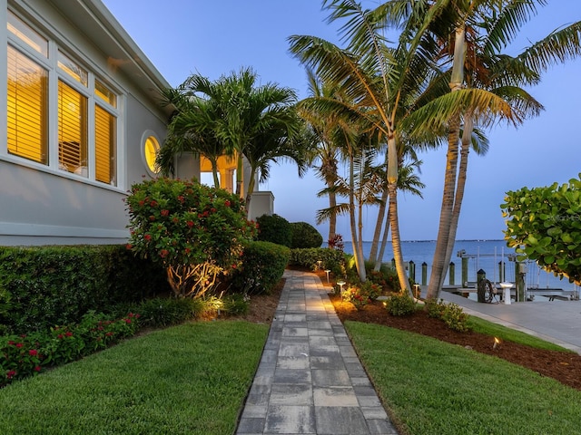 view of property's community with a yard, a water view, and a boat dock