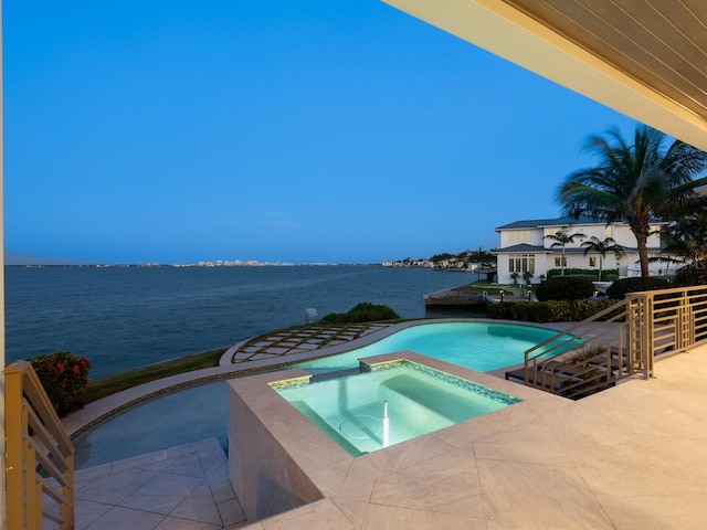 view of pool with a patio area, a water view, and an in ground hot tub