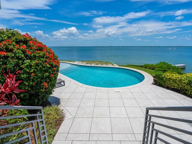 view of swimming pool with a water view and a patio