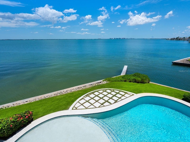 view of pool with a water view and a lawn