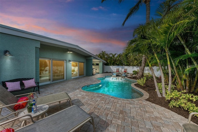 pool at dusk with pool water feature and a patio area