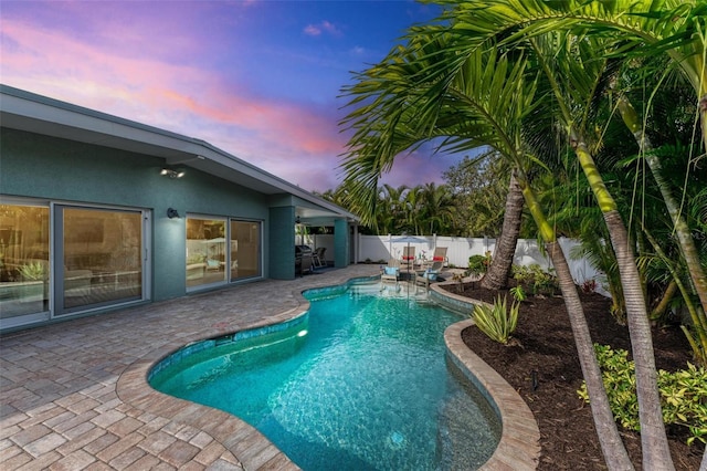 pool at dusk with a patio area