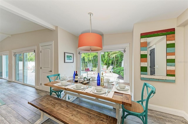 dining room with lofted ceiling with beams and light hardwood / wood-style floors