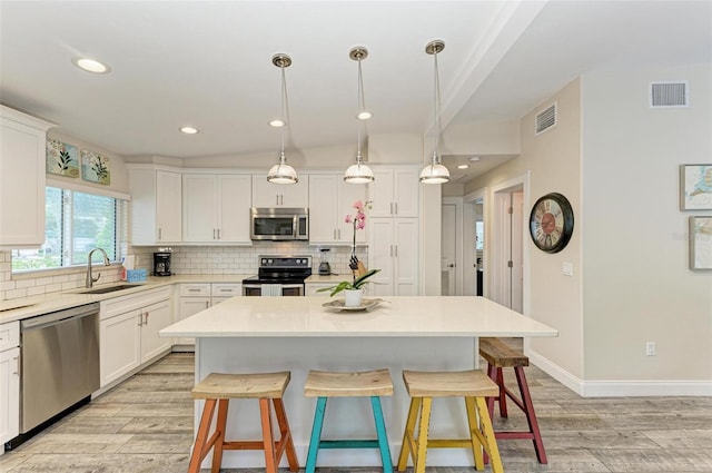 kitchen featuring sink, a kitchen island, decorative light fixtures, and appliances with stainless steel finishes