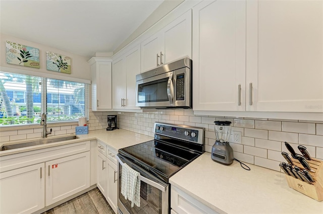 kitchen featuring sink, white cabinetry, stainless steel appliances, and tasteful backsplash