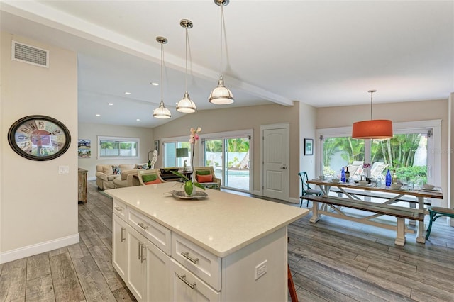 kitchen with beam ceiling, hanging light fixtures, a kitchen island, dark hardwood / wood-style floors, and white cabinets