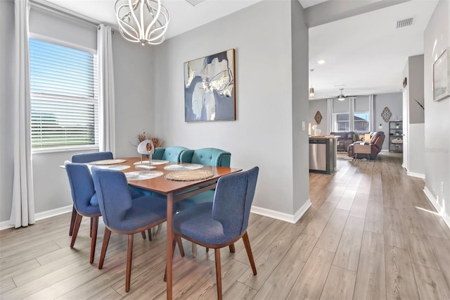 dining area with ceiling fan with notable chandelier and light hardwood / wood-style floors