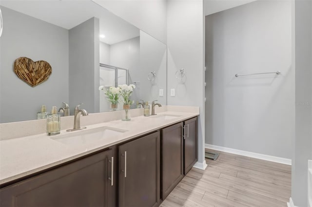 bathroom with hardwood / wood-style floors, vanity, and an enclosed shower