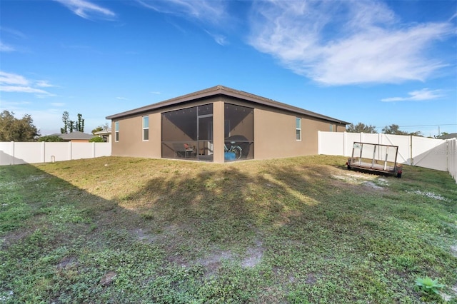 rear view of house featuring a sunroom and a yard