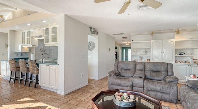 living room with built in shelves, ceiling fan, and light tile patterned flooring