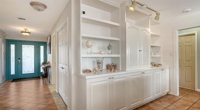 bar featuring white cabinetry, light tile patterned flooring, and built in features