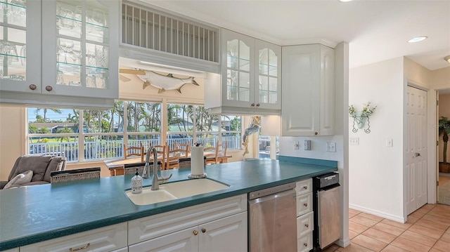 kitchen featuring white cabinets, light tile patterned flooring, stainless steel dishwasher, and sink