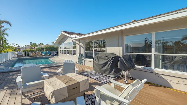 wooden deck featuring a fenced in pool and area for grilling