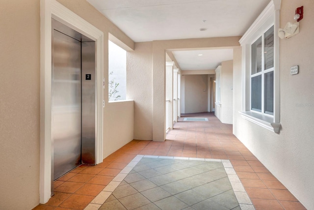 hall with light tile patterned floors and elevator