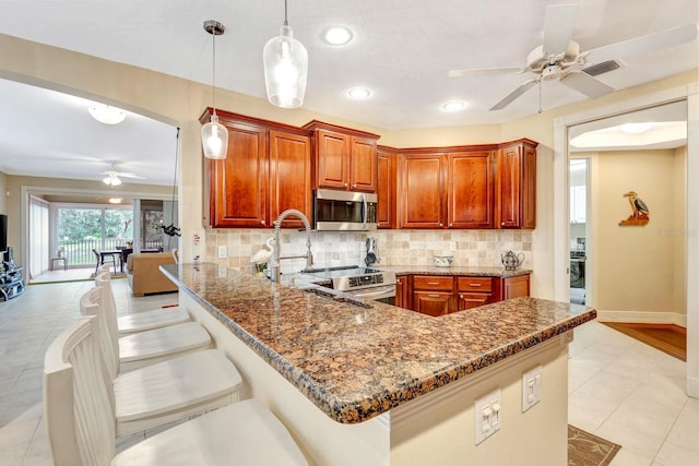 kitchen featuring sink, hanging light fixtures, decorative backsplash, a kitchen bar, and kitchen peninsula