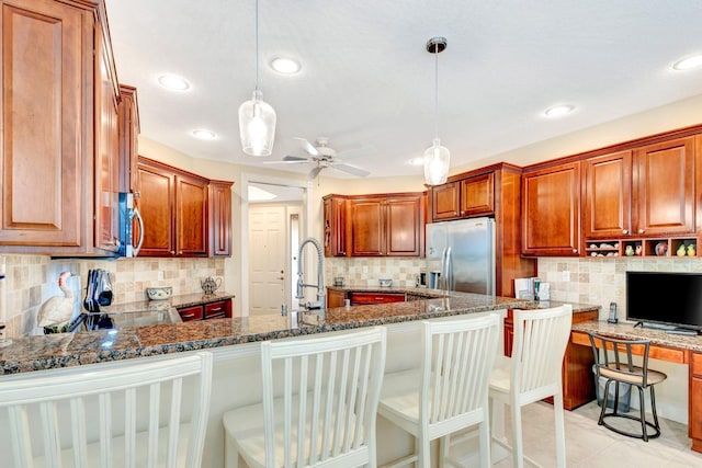 kitchen with a kitchen breakfast bar, stainless steel fridge with ice dispenser, hanging light fixtures, and dark stone counters