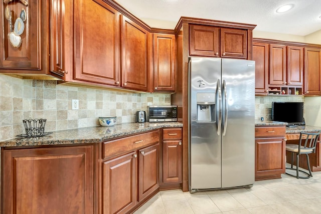 kitchen featuring decorative backsplash, stainless steel refrigerator with ice dispenser, dark stone counters, and light tile patterned flooring