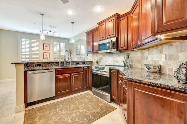 kitchen with pendant lighting, sink, light tile patterned floors, kitchen peninsula, and stainless steel appliances