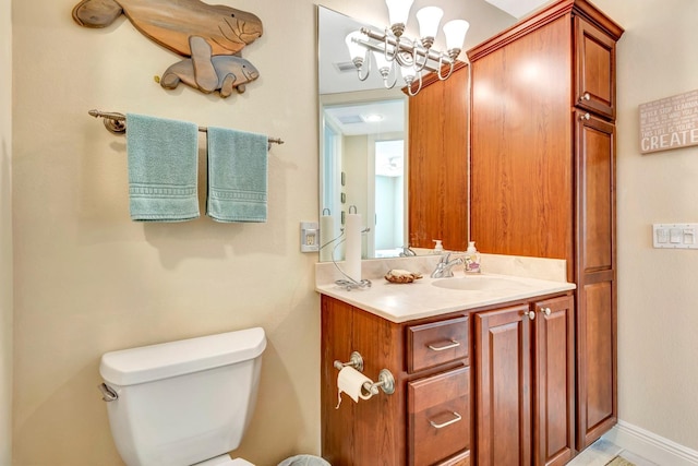 bathroom with vanity, toilet, and a notable chandelier