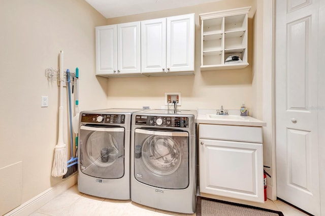 clothes washing area featuring separate washer and dryer, sink, light tile patterned floors, and cabinets