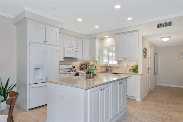 kitchen with white cabinetry, light stone counters, crown molding, white appliances, and a kitchen island