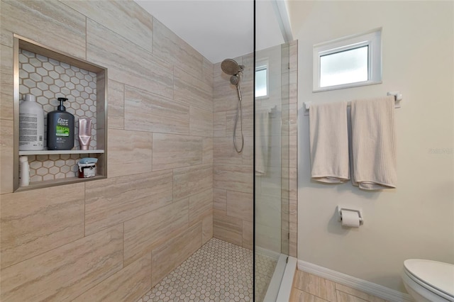 bathroom featuring tiled shower and toilet