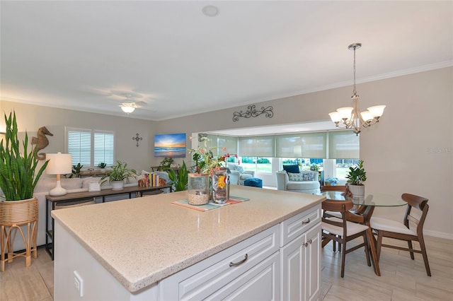 kitchen featuring crown molding, white cabinetry, a center island, and hanging light fixtures