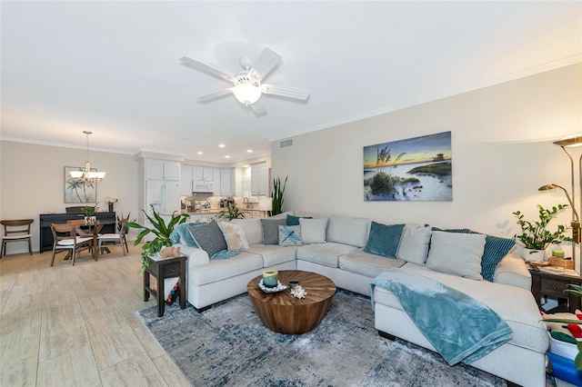 living room with ceiling fan with notable chandelier, light hardwood / wood-style floors, and ornamental molding