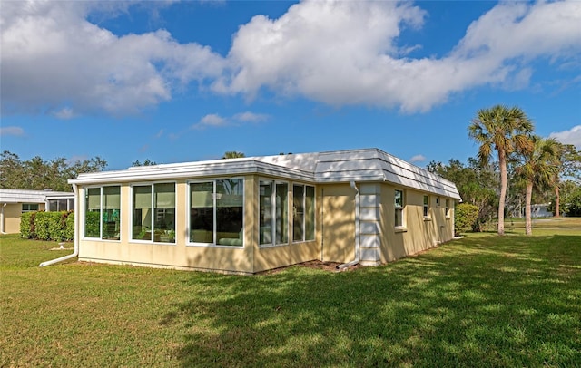 back of property with a sunroom and a lawn