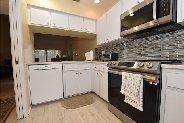 kitchen with backsplash, light hardwood / wood-style floors, sink, appliances with stainless steel finishes, and white cabinets