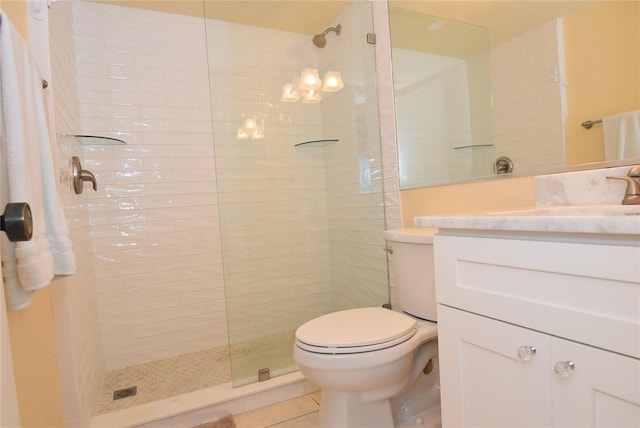 bathroom featuring toilet, a tile shower, tile patterned floors, and vanity