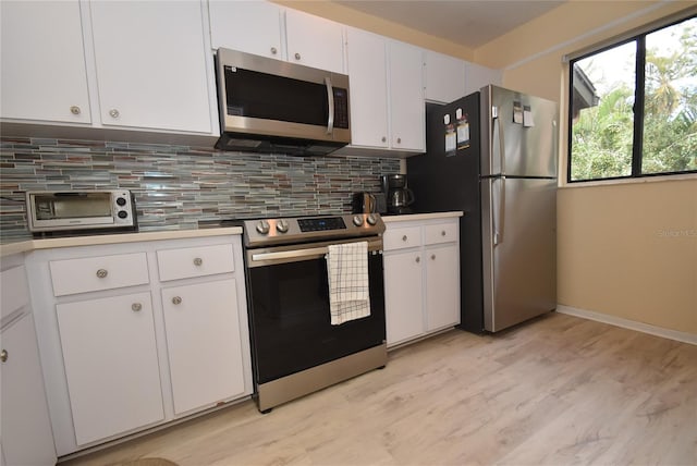 kitchen featuring light wood-type flooring, stainless steel appliances, decorative backsplash, and white cabinets