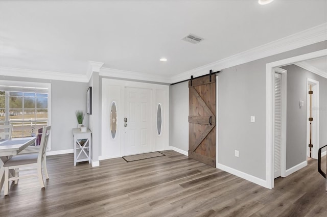 foyer with a barn door, wood-type flooring, and crown molding