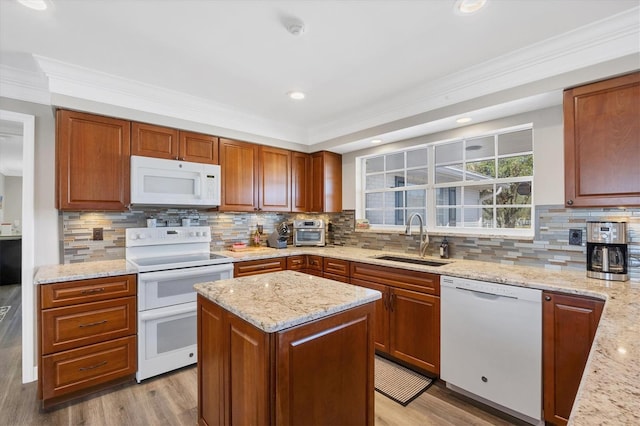 kitchen featuring white appliances, sink, decorative backsplash, light stone countertops, and a kitchen island