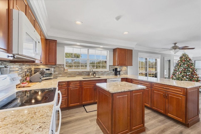 kitchen with white appliances, tasteful backsplash, a kitchen island, and sink