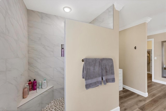 bathroom featuring a tile shower, hardwood / wood-style flooring, and crown molding