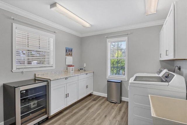 washroom with wine cooler, separate washer and dryer, crown molding, and cabinets