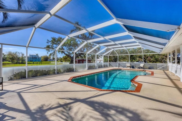 view of pool featuring glass enclosure, a water view, and a patio