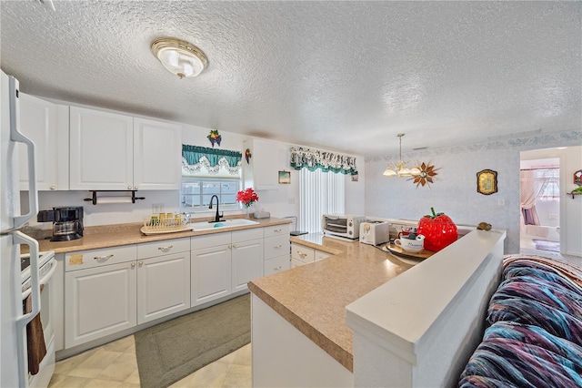 kitchen with an inviting chandelier, sink, hanging light fixtures, white fridge with ice dispenser, and white cabinetry