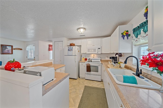 kitchen with white cabinetry, sink, a center island, a textured ceiling, and white appliances