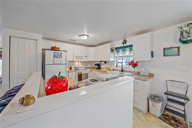 kitchen with white appliances, sink, a textured ceiling, light hardwood / wood-style floors, and white cabinetry