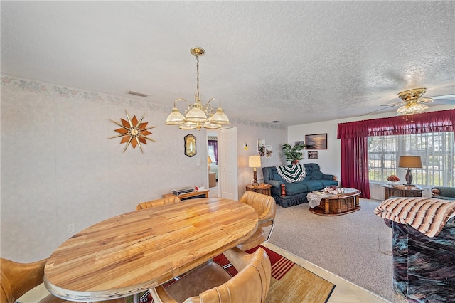 dining space featuring ceiling fan with notable chandelier and a textured ceiling