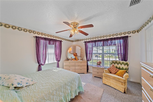 carpeted bedroom with multiple windows, ceiling fan, and a textured ceiling