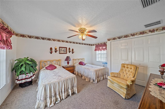 bedroom featuring carpet flooring, ceiling fan, a closet, and a textured ceiling